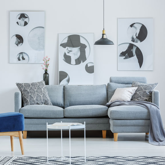 Designer`s living room with posters and grey sofa.